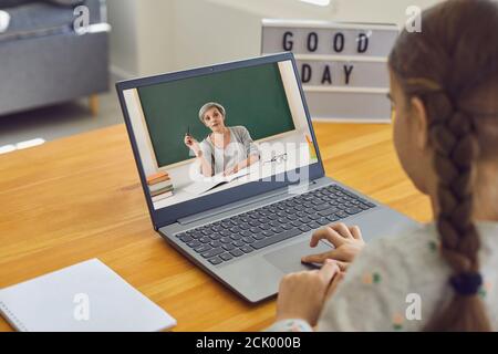 Scuola domestica. Bambina che guarda una lezione online su un computer portatile in interni. Studente elementare che partecipa alla classe web Foto Stock