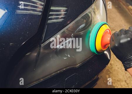 Pulizia dei fari dell'auto con una macchina con buffer di potenza al servizio auto. Foto Stock