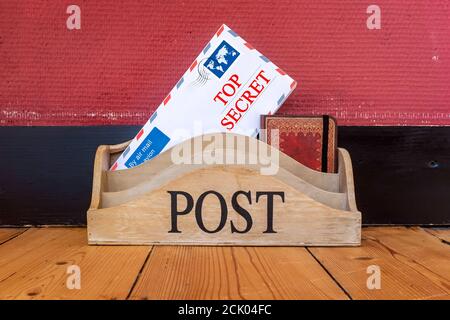 Le parole Top Secret stampate su una busta in un contenitore di legno. Foto Stock