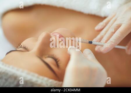 Cosmetologa che fa iniezione del riempitivo del botox nelle labbra femminili con la siringa in salone di bellezza Foto Stock