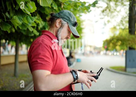 Uomo che guarda e naviga un drone. Uomo bearded che aziona il drone tramite telecomando. Foto Stock