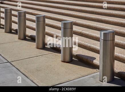 Ai piedi dei gradini di una piazza, le colonnine in acciaio inossidabile limitano l'accesso veicolare a un edificio di uffici a Lower Manhattan, New York. Foto Stock