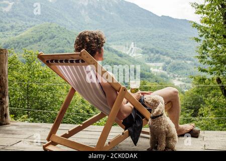 indietro view photo. un cane guarda il suo proprietario che sta trascorrendo le sue vacanze estive su un bellissimo paesaggio. fedele amico e devozione concetto. Foto Stock