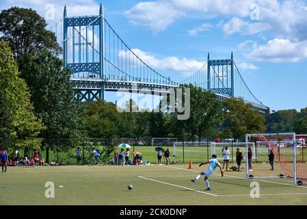 WARDS ISLAND, NY USA - SETTEMBRE 12 2020: Atleti che giocano a calcio sui campi di Wards Island, New York, con il ponte Robert F. Kennedy nel backgro Foto Stock
