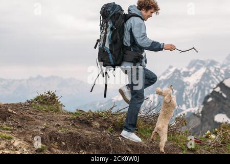 sorridente bel ragazzo sta giocando con il cane sulla collina. vista laterale foto. passime. concetto di tempo libero Foto Stock