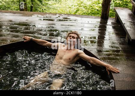 giovane bel maschio godendosi in bagno su un bellissimo paesaggio. Foto Stock