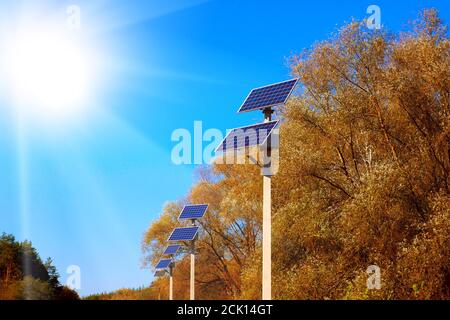 Luci di strada con pannelli solari. Una fila di pannelli solari vicino alla strada contro un cielo blu chiaro. Foto Stock
