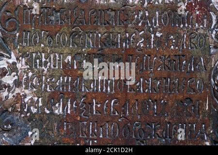 Frammento di vecchia lettera slavica cirillica su lastra di pietra intemperie sul muro dell'antico tempio. Foto Stock
