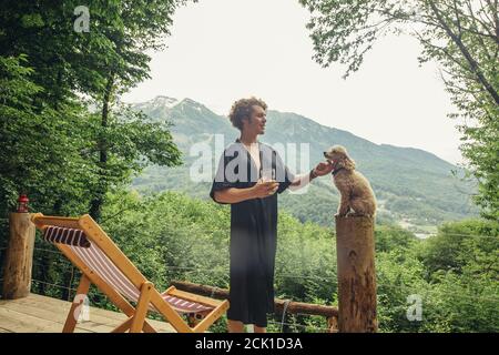 il giovane e simpatico uomo con il suo cane si diverte accanto alla sdraio nella zona del resort. chiudi vista laterale foto.concetto di togetherness Foto Stock