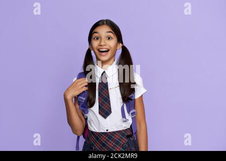 Entusiasta ragazza indiana della scuola tiene lo zaino isolato su sfondo viola. Foto Stock