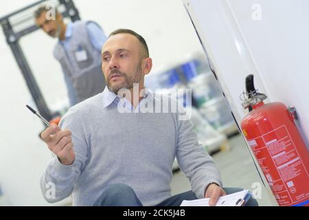 ispettore maschio che controlla l'estintore in ufficio Foto Stock