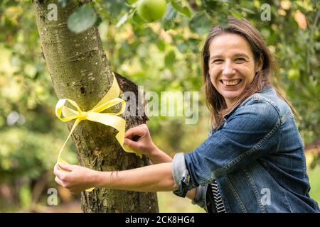 Achternmeer, Germania. 11 Settembre 2020. Simone Malz dell'associazione cittadina Achternmeer-Harbern 1 ha attaccato il "nastro giallo" ad un albero di mele. Il nastro sull'albero deve richiamare l'attenzione sul fatto che la frutta può essere raccolta e mangiata da tutti. Credit: Mohssen Assanimoghaddam/dpa/Alamy Live News Foto Stock