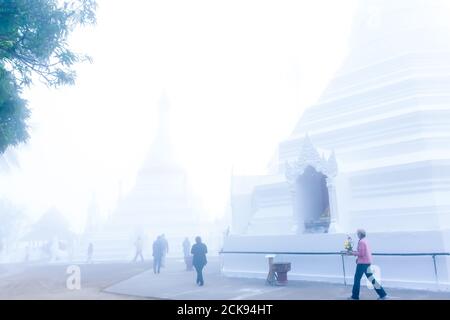 buddisti asiatici che camminano con mazzo di fiori intorno all'antica pagoda di Wat Phrathat Doi Kong Mu, Mae Hong Son, Thailandia. Foto Stock