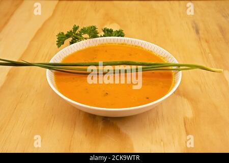 Una ciotola di zuppa di verdure accompagnata da erbe fresche di prezzemolo e erba cipollina Foto Stock