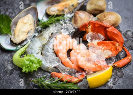 Buffet di pesce fresco crudo con ingredienti al limone rosmarino erbe e. Spezie / frutti di mare crostacei su ghiaccio congelato con gamberi gamberi griffe di granchio gabbie di conchiglia s Foto Stock