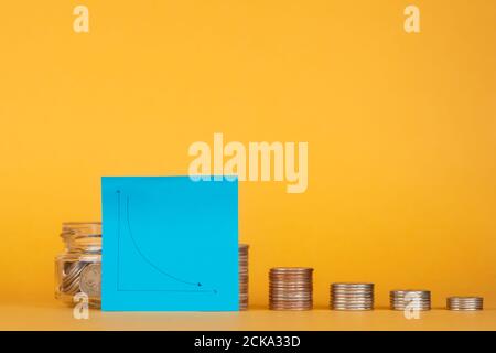 crisi finanziaria. pila di monete con un grafico per una caduta. Foto Stock