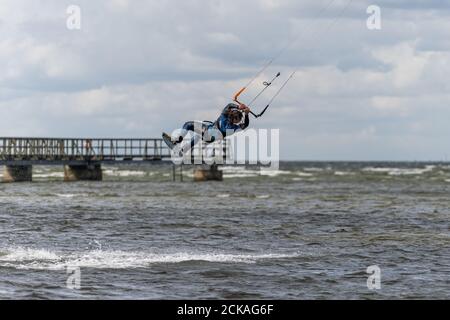 Malmo, Svezia - 23 agosto 2020: Un kitesurfer salta in alto in acqua in una giornata ventosa in cui molte persone cogliano l'opportunità di praticare sport acquatici Foto Stock