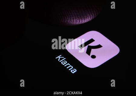 Logo dell'app Klarna visualizzato sullo schermo e punta del dito sfocata sopra di essa. Messa a fuoco selettiva. Macro. Concetto. Foto Stock