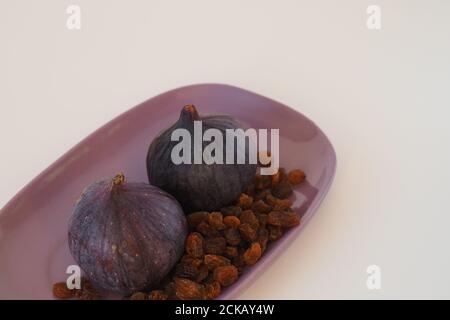 Frutta. Fiche e uvetta su un piatto viola. Sfondo bianco. Primo piano. Foto di alta qualità Foto Stock