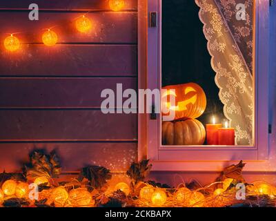 Felice Halloween! La finestra di una casa decorata per la vacanza. Zucche, ghirlanda, candele e foglie d'autunno. Foto Stock