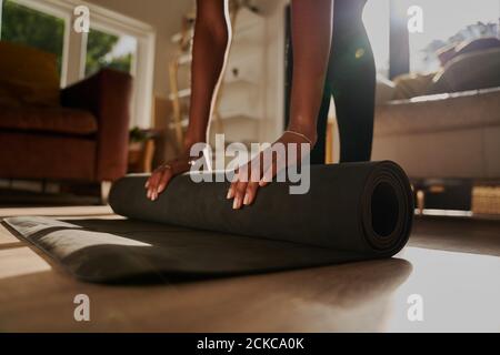 Closeup di mani di giovane donna pieghevole fitness mat dopo allenati a casa tua Foto Stock