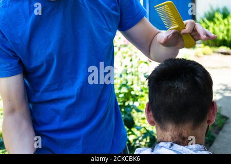 il barbiere taglia il ragazzo con un regolacapelli Foto Stock