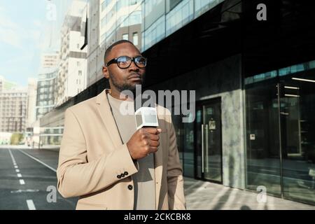 Reporter africano che tiene il microfono e parla lui che lavora nelle notizie canale Foto Stock