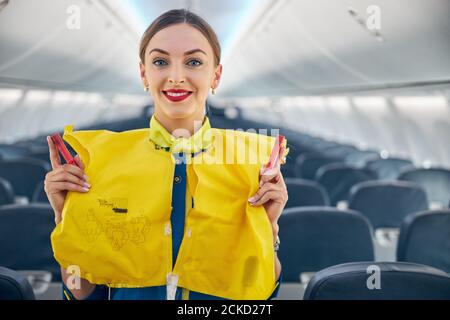 Primo piano ritratto di air hostess che dimostra le procedure di sicurezza a. passeggeri prima del decollo del volo Foto Stock