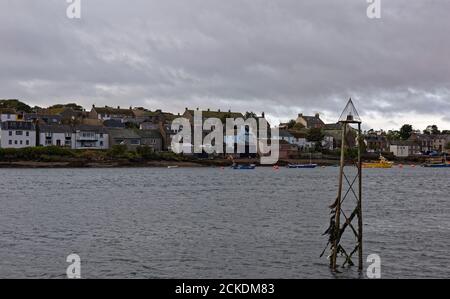 Uno dei vecchi marcatori di navigazione in metallo e luce sul lato settentrionale del fiume South Esk ad alta marea, con le case di Ferryden nel backgro Foto Stock