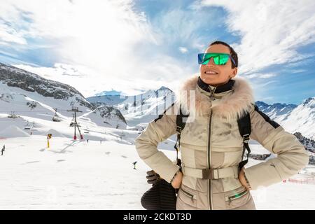 Giovane adulto bello felice attraente caucasica sorridente donna saltando saltando in alto come una stella contro il panorama della stazione sciistica vista mozzafiato Foto Stock