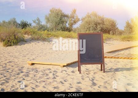 Menu black board colore nero per testo, messaggio o pubblicità. Spiaggia di sabbia sul mare. Giorno di sole. Foto Stock