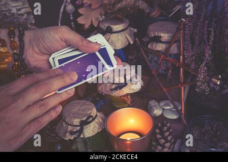 La mano della donna sta tenendo il mazzo delle carte del tarocco o dell'oracolo che effettuano il fortunetelling. Tinta a colori freddi Foto Stock