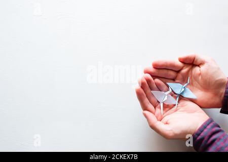 uomo che tiene una gru di origami su uno sfondo bianco con spazio per il testo Foto Stock