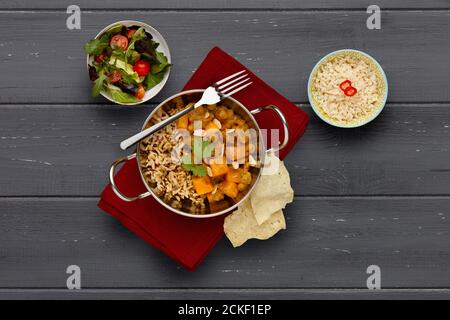 Un piatto tradizionale di blati, farcito con delizioso curry vegetale e riso rustico, guarnito con un filo di corriandolo, con un contorno di riso e una b Foto Stock