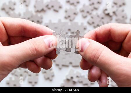 mani di uomo d'affari cercando di raccogliere pezzi del puzzle su uno sfondo di altri dettagli Foto Stock