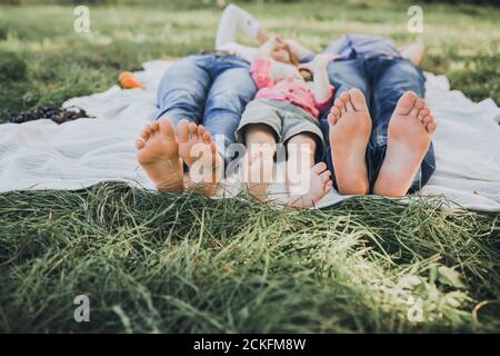 i piedi di un ragazzo, di una mamma e di un papà si stendono su un copriletto bianco Foto Stock