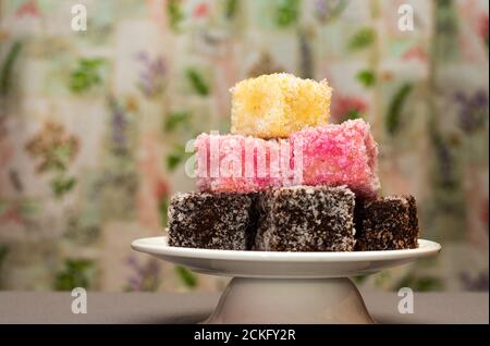 Primo piano del colorato dessert australiano Lamingtons accatastato e servito su una base per torte Foto Stock