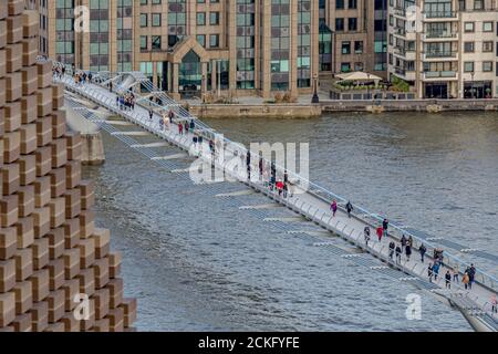 Persone che attraversano il Millennium Footbridge, un ponte sospeso in acciaio sul Tamigi a Londra, che collega Bankside con la City di Londra Foto Stock