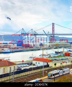 Gabbiani sul porto commerciale di Lisbona, container di navi e gru per il trasporto merci, skyline con il 25 aprile Ponte e fiume Tago, Portogallo Foto Stock