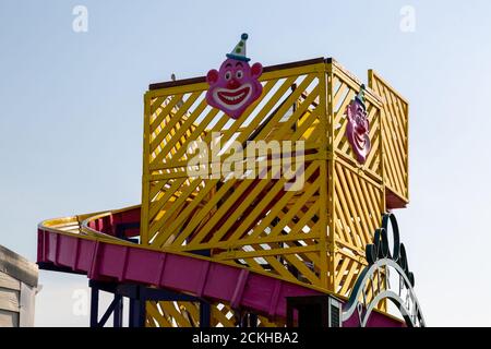 La parte superiore di uno scivolo funfair per bambini o di uno scheletro helter con un viso clown su di esso Foto Stock