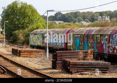 Un vecchio treno sotterraneo o metropolitana coperto di graffiti il lato di una pista ferroviaria Foto Stock