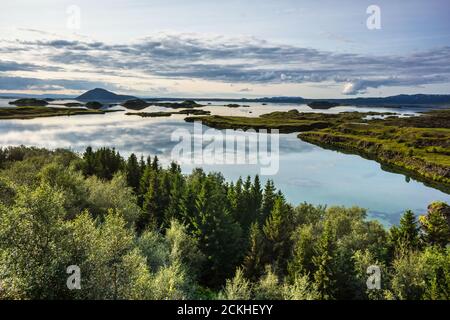 Myvatn lago che druola un tramonto nuvoloso con il riflesso di nuvole sulla sua superficie ancora, Islanda Foto Stock