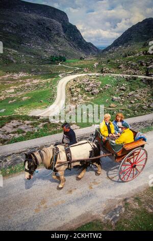 Un pony tradizionale e una trappola attraversa il Gap of Dunloe a Killarney con i turisti, Irlanda. Foto Stock