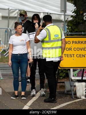 I membri del pubblico parlano con il personale mentre si accodano in una struttura di test del coronavirus all'Università di Birmingham. Foto Stock