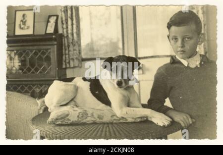 Cartolina del 1900 iniziale di ragazzo che indossa un ponticello lavorato a maglia con il suo cane Parson Russell del terrier dell'animale domestico,- posizione sconosciuta, europea, intorno 1920's 1930. Foto Stock