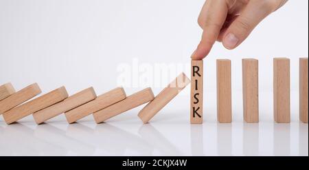 effetto domino e concetto di gestione del rischio. manager smette di cadere cubi di legno con il dito. Foto Stock