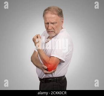 Closeup uomo anziano con infiammazione gomito colorato in rosso sofferenza da dolore e reumatismi isolati su sfondo grigio con spazio di copia Foto Stock