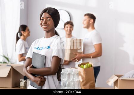 Fuoco selettivo del volontario afroamericano che tiene gli appunti vicino alle donazioni in centro di carità Foto Stock