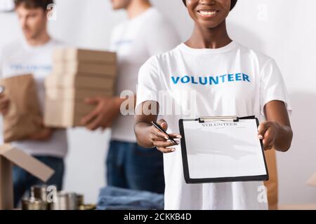 Fuoco selettivo del volontario afroamericano che tiene gli appunti e la penna in centro di carità Foto Stock