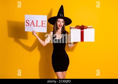 Ritratto di lei bella bella bella snella ragazza allegra wizard che tiene nelle mani la carta di vendita giftbox affare giorno di compleanno evento isolato Foto Stock